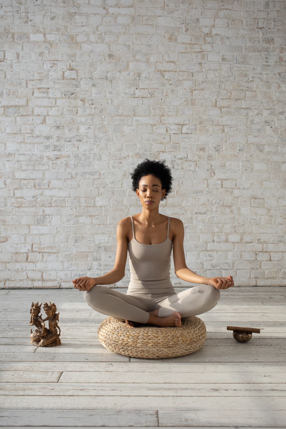 A woman meditating cross-legged on a cushion in a calm, minimalist room